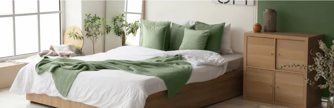 made bed with pale sheets and green pillow